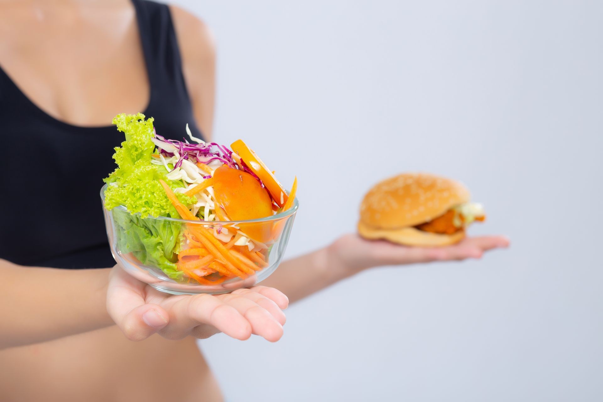 Closeup woman slim shape with diet choosing fresh salad vegetable and hamburger isolated on white background, food healthy with control for weight loss with calories, nutrition and lifestyle concept.